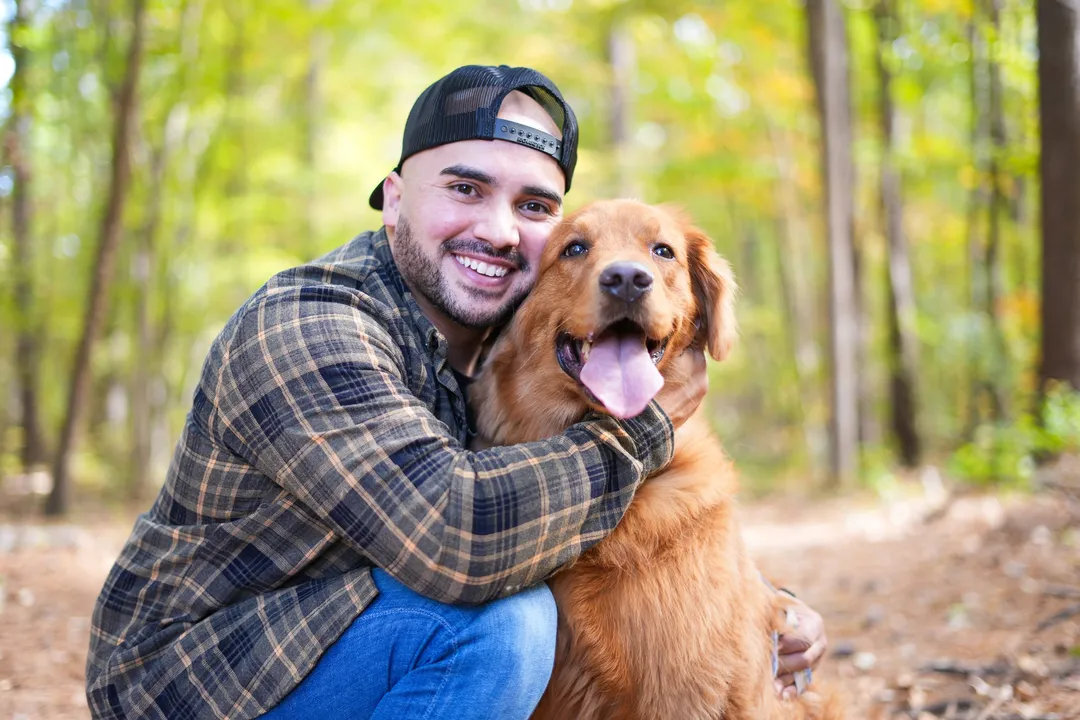 Mario hugging Jax the golden retriever on a leafy forest trail