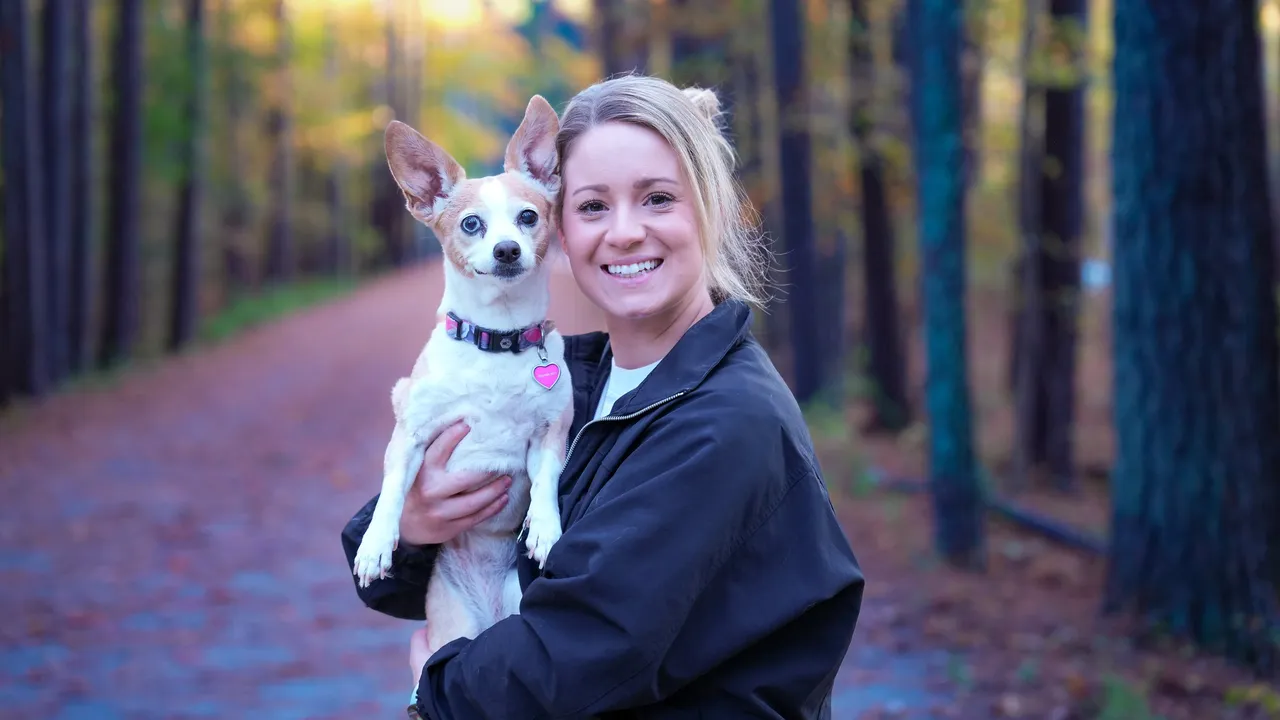 Ashley holding Ella at dusk on a pine-lined trail