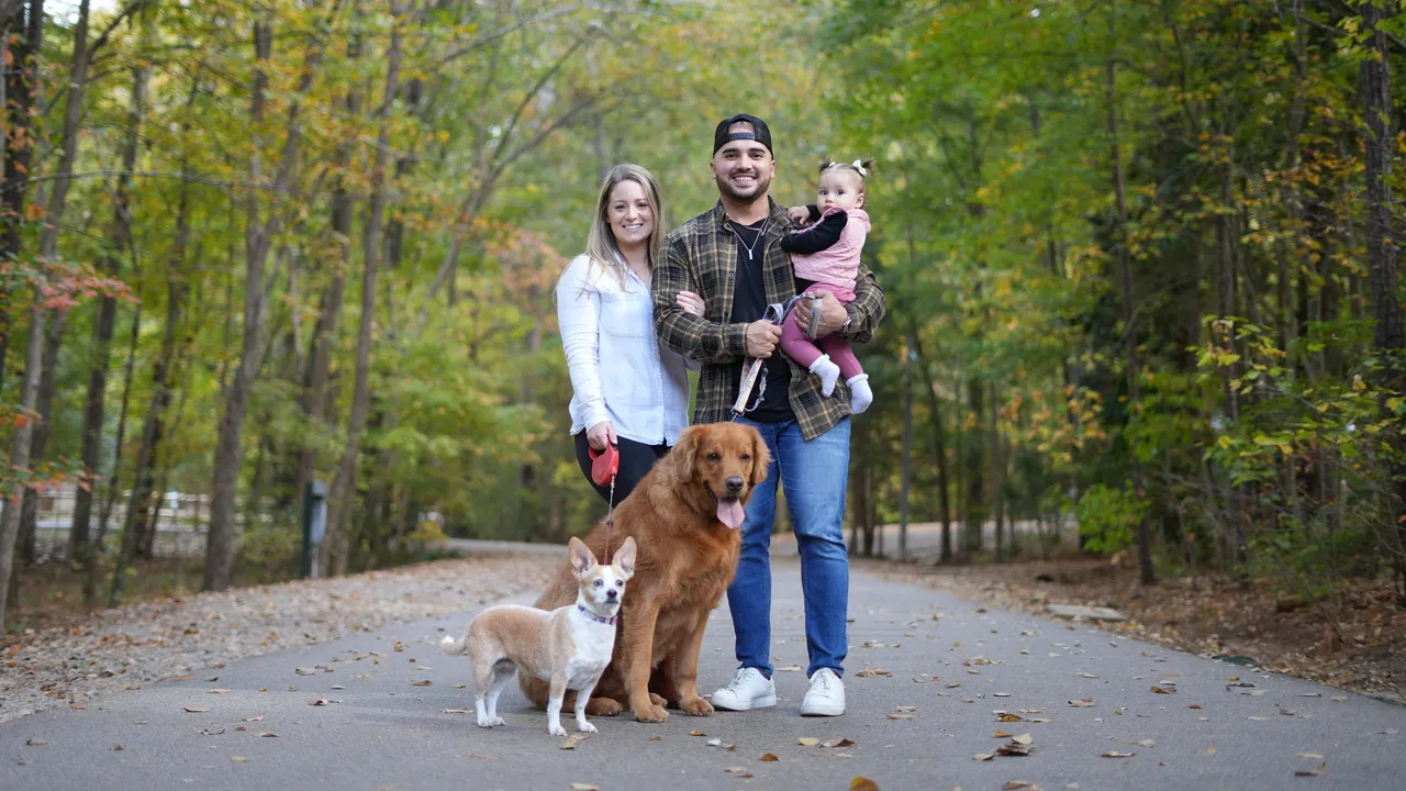 The family standing on a tree-lined path with both dogs