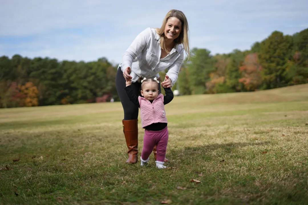 Ashley helping Sloan take her first steps across the grass
