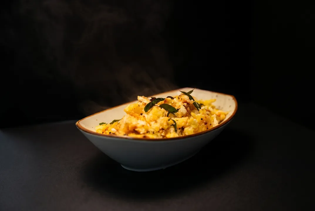 A steaming bowl of egg podimas with mustard seeds and crisped curry leaves